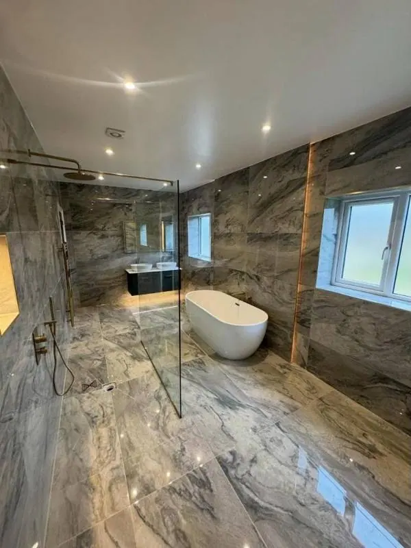 Marble-effect wet room with freestanding bath and brushed brass shower, every joint sealed